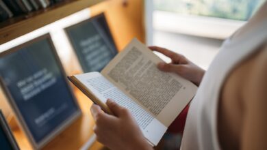 A person reading an open book among the shelves of a library